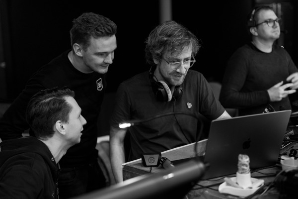 Four people gathered around a laptop at the control desk.